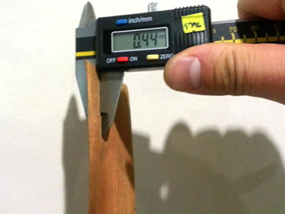 A piece of brass wire mesh is measured by calipers.