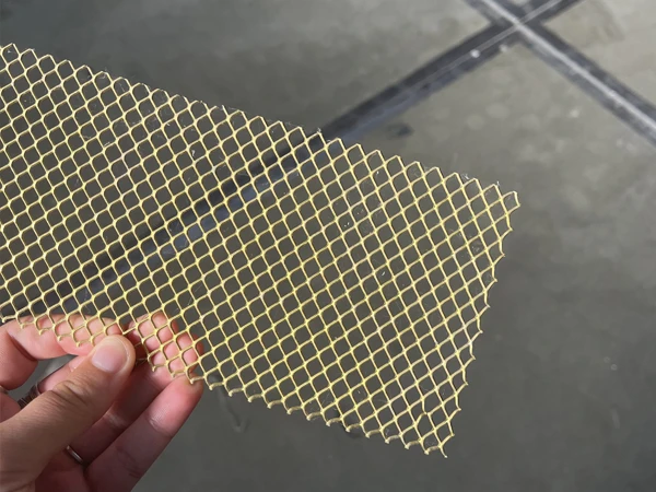 A person holding a brass expanded metal mesh rectangle sample