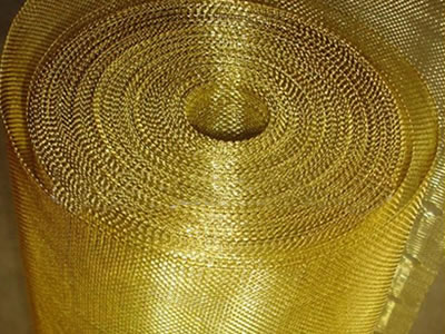 A roll of brass insect screen with small holes is on the ground.