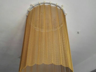 The picture shows a round brass metal mesh curtain hanging on ceiling for lamp decoration.
