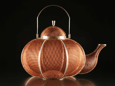 A teapot made of copper mesh.