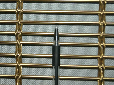 A woven brass decorative cable mesh with small openings is made with three ropes across a rod every strand.