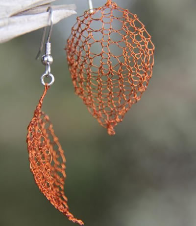 The picture shows a pair of earring made of copper knitted wire mesh.