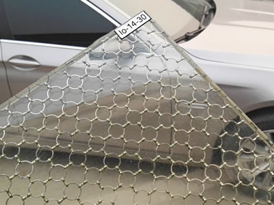 A piece of ring mesh in glass beside a car.