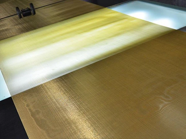 Woven brass wire mesh screen is being checked for scars